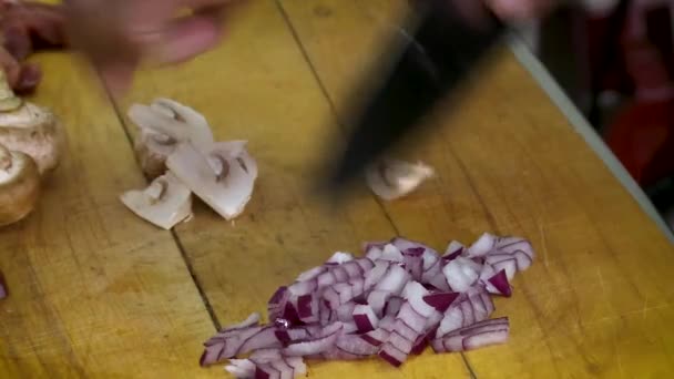 Visão de perto de mãos masculinas cortando cebolas em uma mesa de madeira . — Vídeo de Stock