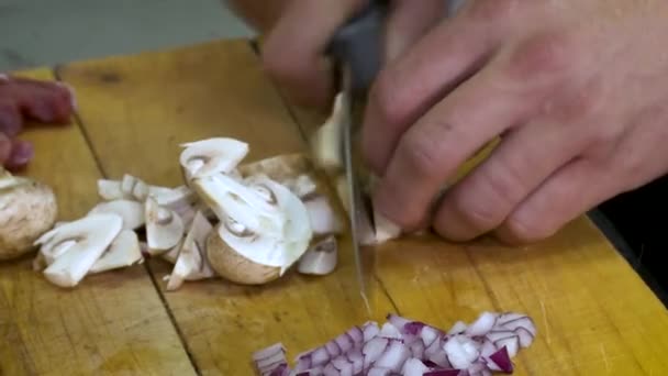 Großaufnahme von männlichen Händen, die Champignon auf einem Holztisch hacken. — Stockvideo