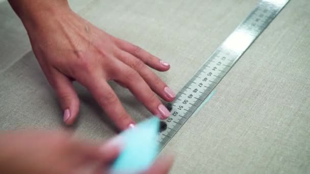 Gros plan des mains féminines avec manucure marquant le tissu à la craie. — Video