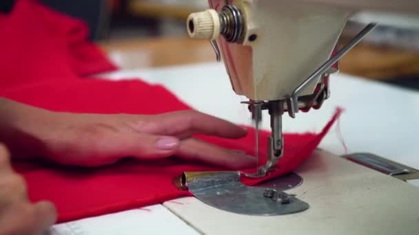 Close-up van vrouwelijke handen die aan een naaimachine werken. — Stockvideo