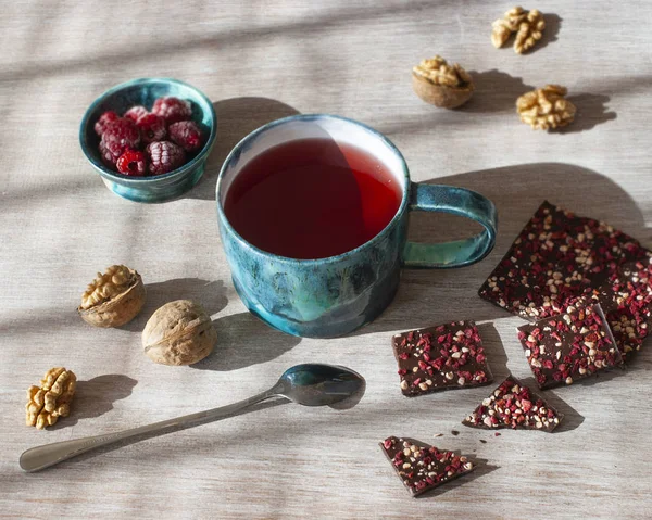 raspberry tea, chocolate, nuts and raspberries on a wooden table, selective focus.