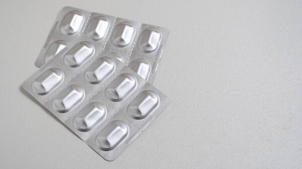 capsule pills medicine in silver aluminium blister pack isolated on white background with copy space for text. Pharmaceutical packing manufacturing concept. Blister pack with pills isolated on white. Empty blister packs isolated on white background.