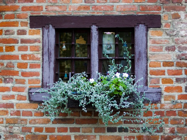 Vintage window with flower pots, old cute window on a brick wall in Kaunas, Lithuania