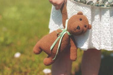 Bir buket ve bunun dışında bir çayır çiçekli bir kız elinde bakmak bir örme ayı ile bir el çantası close-up. Vintage.