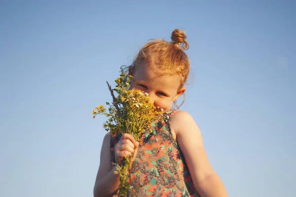 Giovane ragazza felice con un fiore in mano contro il cielo blu — Foto Stock