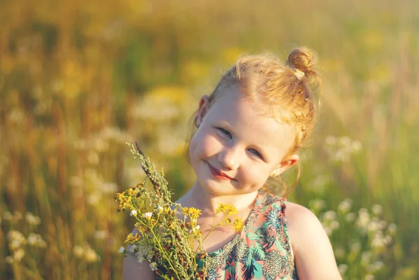 Felice ragazza con un fiore e giocattolo in mano contro l'erba verde — Foto Stock