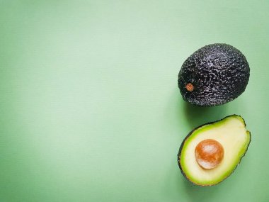Hass avokado yeşil bir arka plan üzerinde. Vegan hayat. Sağlıklı yiyecekler. Gıda yeşil.