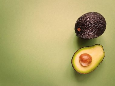 Hass avokado yeşil bir arka plan üzerinde. Vegan hayat. Sağlıklı yiyecekler. Gıda yeşil.