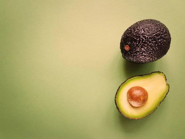 Hass avokado yeşil bir arka plan üzerinde. Vegan hayat. Sağlıklı yiyecekler. Gıda yeşil.
