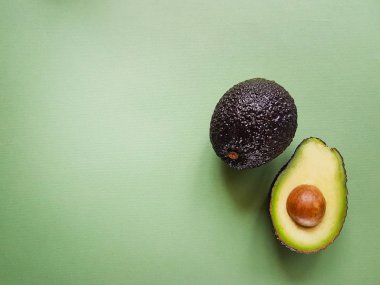Hass avokado yeşil bir arka plan üzerinde. Vegan hayat. Sağlıklı yiyecekler. Gıda yeşil.