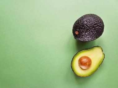 Hass avokado yeşil bir arka plan üzerinde. Vegan hayat. Sağlıklı yiyecekler. Gıda yeşil.