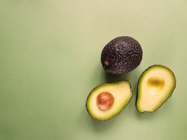 Hass avokado yeşil bir arka plan üzerinde. Vegan hayat. Sağlıklı yiyecekler. Gıda yeşil.