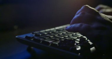 Klavyede geceleri yazarak. Koyu arka plan aydınlatma. Yakın çekim