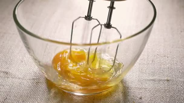 Electric mixer beaters eggs in glass bowl. Cooking, close-up. Slow motion — Stock Video