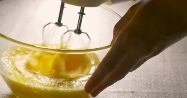 Mélangeur électrique bat les œufs dans un bol en verre. Cuisine, gros plan — Video