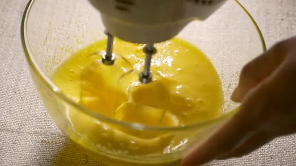 Mezclador eléctrico batidor huevos en tazón de cristal. Cocinando, de cerca. Movimiento lento — Vídeo de stock