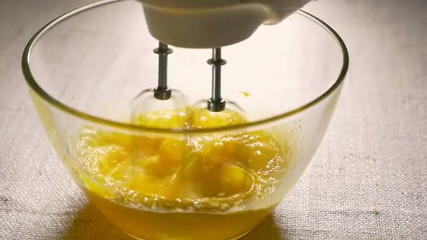 Electric mixer beaters eggs in glass bowl. Cooking, close-up. Slow motion — Stock Video