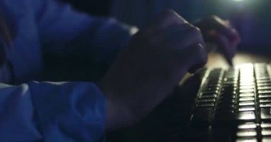 Klavyede geceleri yazarak. Koyu arka plan aydınlatma. Yakın çekim