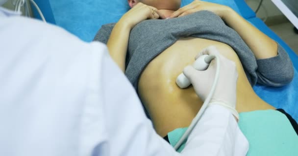 Doctor haciendo un ultrasonido diagnóstico de estómago. Mirando al abdomen delgado de las mujeres jóvenes en la pantalla del dispositivo de ultrasonido en el hospital — Vídeo de stock