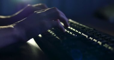 Klavyede geceleri yazarak. Koyu arka plan aydınlatma. Yakın çekim