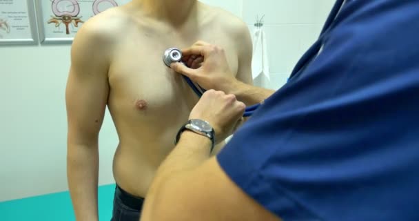 Лікар клініки, який досліджує чоловіка стетоскопом — стокове відео