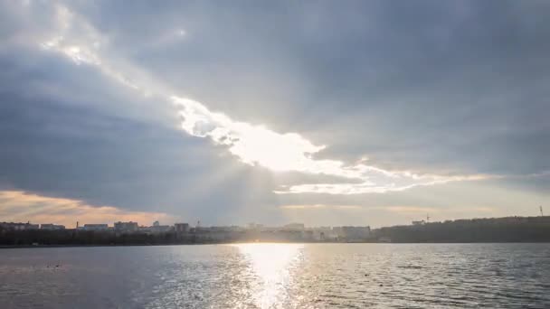 Uskomattomia auringonsäteitä kaupungin järvimaiseman yllä. Aikajänne — kuvapankkivideo