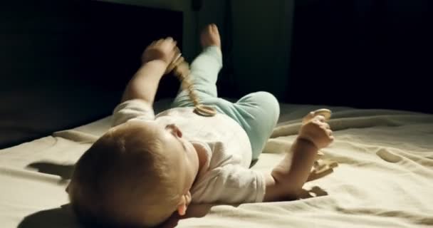 Close-up de adorável bebê curioso brincando com brinquedo de madeira na cama. Pequeno bebê brincando com brinquedos de madeira à noite no quarto escuro — Vídeo de Stock