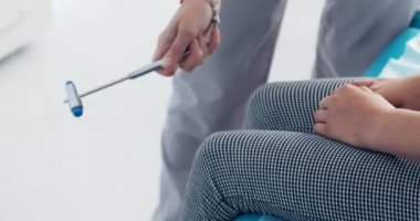 Doktor nörolog çocuk hastanın diz üzerinde bir çekiç ile musluklar inceler