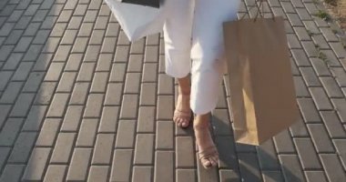 Elinde alışveriş çantaları alt görünümü. Güzel, genç kadın dönem satış alımları ile şehir alışveriş ile yürüyor