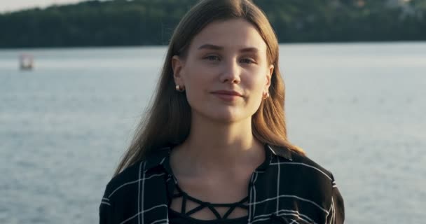 Primer plano retrato de la joven atractiva mujer sonriendo y mirando a la cámara cerca de la playa al atardecer confiada belleza — Vídeos de Stock