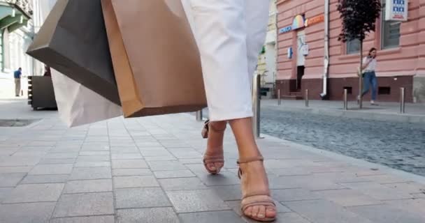 Vista inferior de las bolsas de compras en las manos. Hermosa, mujer joven camina por la ciudad de compras con compras en el período de ventas — Vídeo de stock