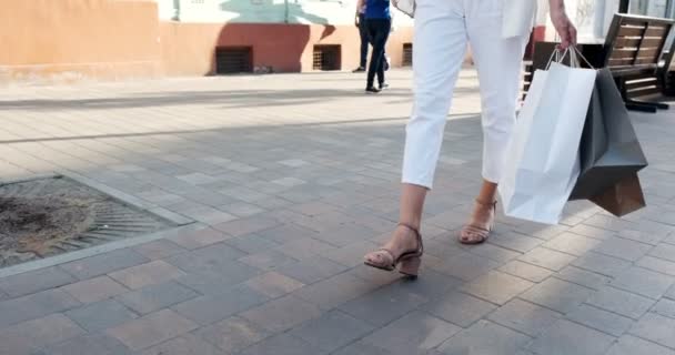 Vue du bas des sacs à provisions dans les mains. Belle, jeune femme marche à travers la ville shopping avec des achats dans les ventes de la période — Video