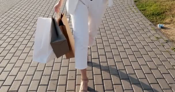 Alsó véve bevásárló táskák a kezében. Gyönyörű, fiatal nő sétál át a várost vásárlás a vásárlások időszakban értékesítés — Stock videók