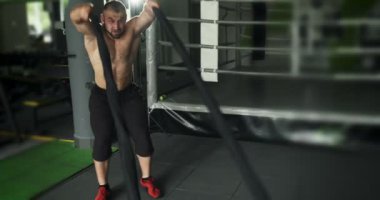 Fitness sporcusu eğitimde savaş halatları kullanır. Yoğun egzersiz egzersiz. Yavaş çekim