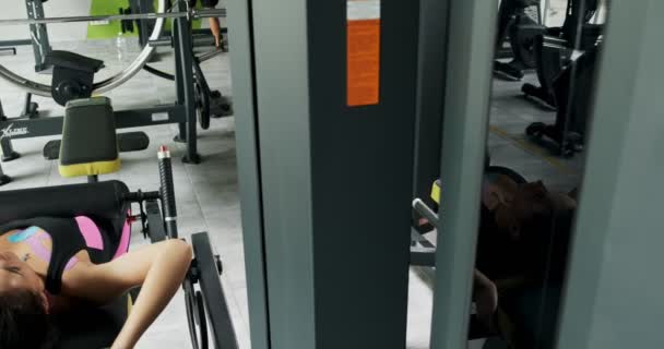 Sterke mooie vrouw trainen spier op sport simulator in Sport Club. Atleet vrouwelijke doen oefening op Fitness machine in de moderne fitnessruimte. Mooi meisje maken oefeningen voor de torso in Fitness Club — Stockvideo