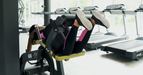 Ισχυρή όμορφη γυναίκα εκπαίδευση μυών στο αθλητικό προσομοιωτή στο Sport Club. Αθλητής θηλυκό κάνει άσκηση σε μηχάνημα γυμναστικής στο σύγχρονο γυμναστήριο. Όμορφο κορίτσι κάνει ασκήσεις για τα πόδια στο Fitness Club — Αρχείο Βίντεο