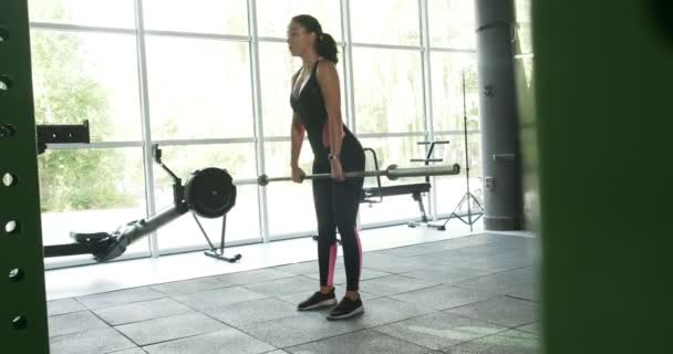 Músculo de entrenamiento de mujer bonita fuerte con barra en el club deportivo. Atleta femenina haciendo ejercicio en el gimnasio moderno — Vídeos de Stock