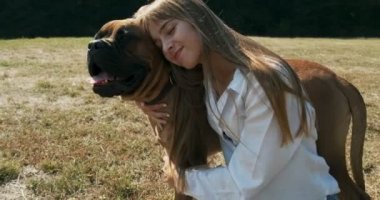 Mutlu genç bayan çimenlerde köpekle oynayarak neşeyle oynuyor. Evcil hayvanla aşk ve arkadaşlık