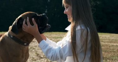 Mutlu genç bayan çimenlerde köpekle oynayarak neşeyle oynuyor. Evcil hayvanla aşk ve arkadaşlık