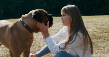 Mutlu genç bayan çimenlerde köpekle oynayarak neşeyle oynuyor. Evcil hayvanla aşk ve arkadaşlık