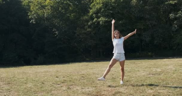 Happy fêmea atrativa faz exercício cambaleante no prado no verão. Movimento lento — Vídeo de Stock