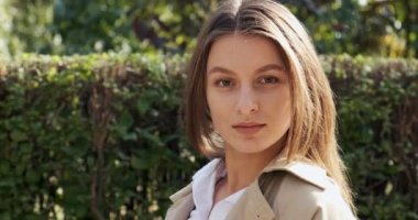 Yeşil tarihi kentsel alanda gülümseyen ve kameraya bakan çekici genç bir kadının portresi. Neşeli, güzel kadın. Kapat.