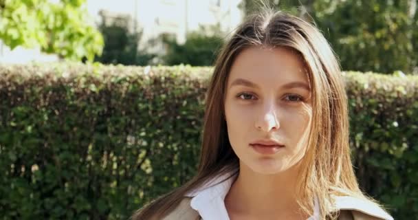 Portrait of young attractive female who looking at the camera on green historical urban area. Close up, sliding camera — Stock Video