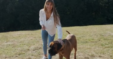 Mutlu genç bayan çimenlerde köpekle oynayıp koşuyor. Evcil hayvanla aşk ve arkadaşlık