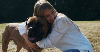 Mutlu genç bayan çimenlerde köpekle oynayarak neşeyle oynuyor. Evcil hayvanla aşk ve arkadaşlık
