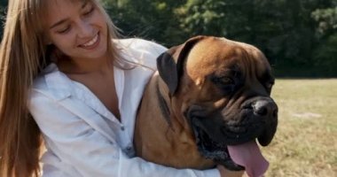 Mutlu genç bayan çimenlerde köpekle oynayarak neşeyle oynuyor. Evcil hayvanla aşk ve arkadaşlık