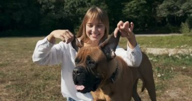 Mutlu genç bayan çimenlerde köpekle oynayarak neşeyle oynuyor. Evcil hayvanla aşk ve arkadaşlık