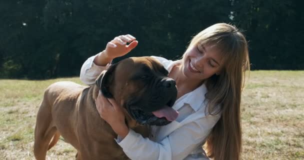 Feliz joven hembra jugando alegremente sentado con el perro en el césped. Amor y amistad con los animales domésticos — Vídeos de Stock