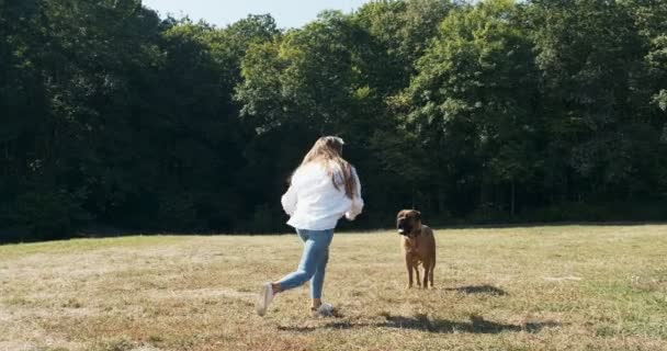 Gelukkig jong vrouwtje vrolijk spelen en rennen met hond in het gazon. Liefde en vriendschap met huisdieren — Stockvideo