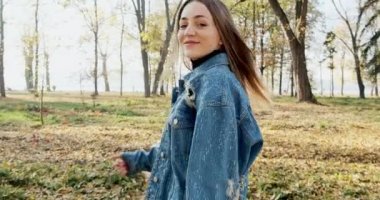 Beni takip et, gülen mutlu genç kız koşuyor ve sonbahar sarı parkında onu takip etmeni istiyor. Çekici bir kadın güneş ışınlarında koşar ve gülümser.